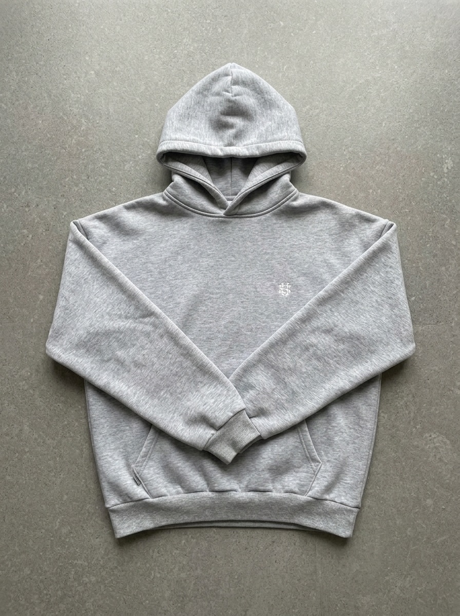 The same grey hoodie re-shot as a flat-lay, squared and centred on grey stone, sleeves folded in across the chest above the kangaroo pocket, hood facing forward
