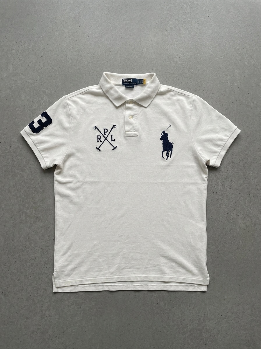 The same white polo re-shot as a flat-lay, squared and centred on a grey stone surface with the sleeves folded inwards
